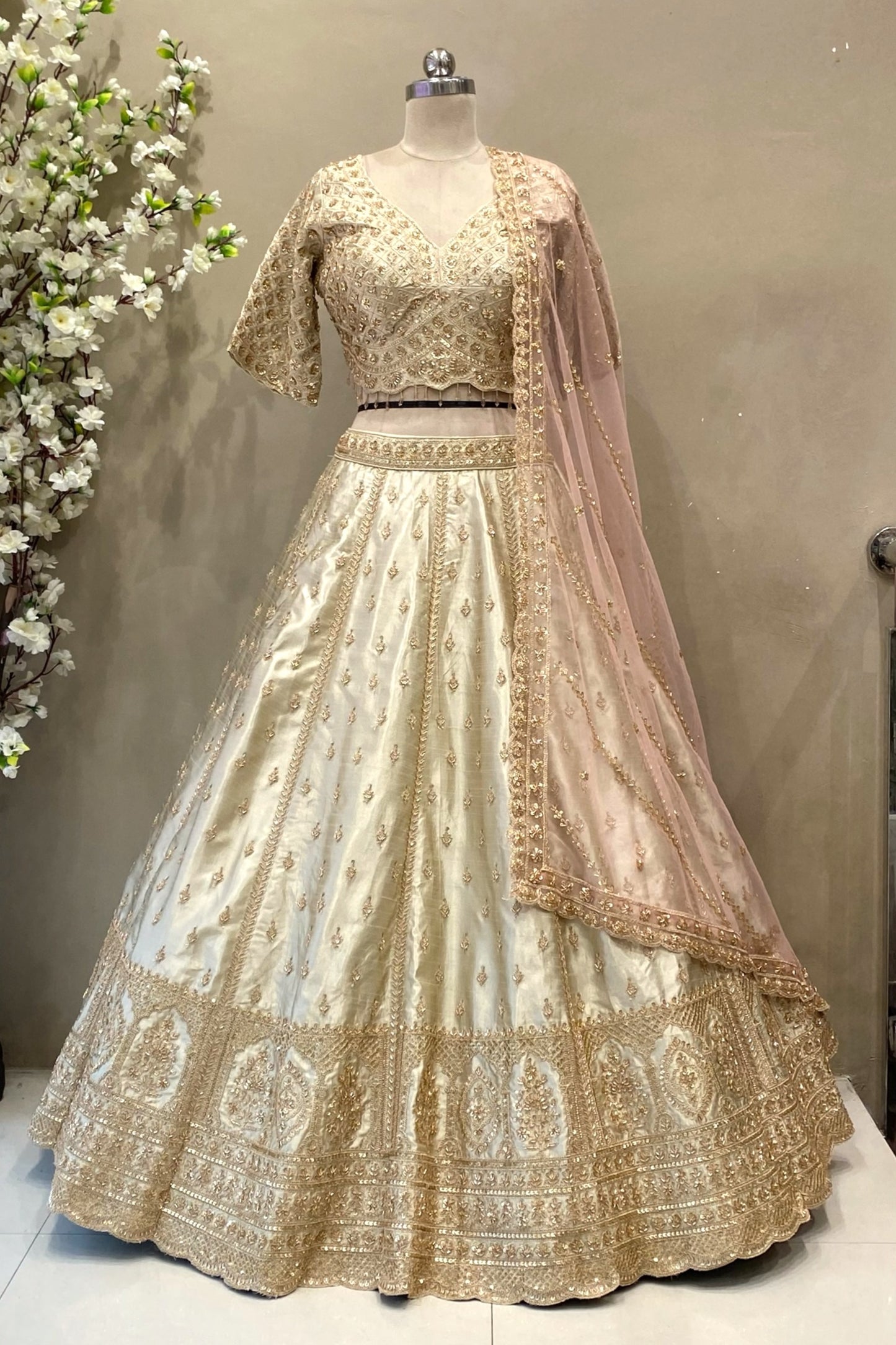 Detailed view of a flared ivory raw silk lehenga skirt featuring rich gold architectural zardosi embroidery and traditional motifs.