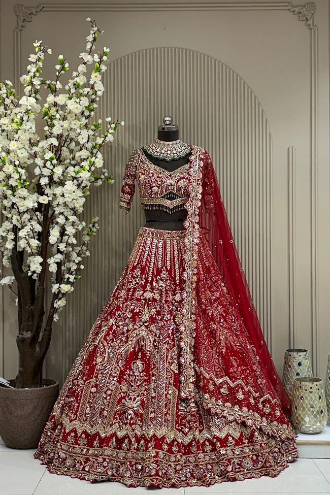 Heritage crimson red bridal lehenga on a mannequin featuring heavy gold cutdana, sequins, and zarkan highlights with cutwork designer sleeves and tassel detailing.