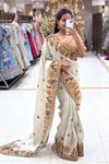 Close-up of a designer ivory V-neck blouse featuring intricate peacock motifs and gold zari work, perfect for a high-end wedding trousseau.