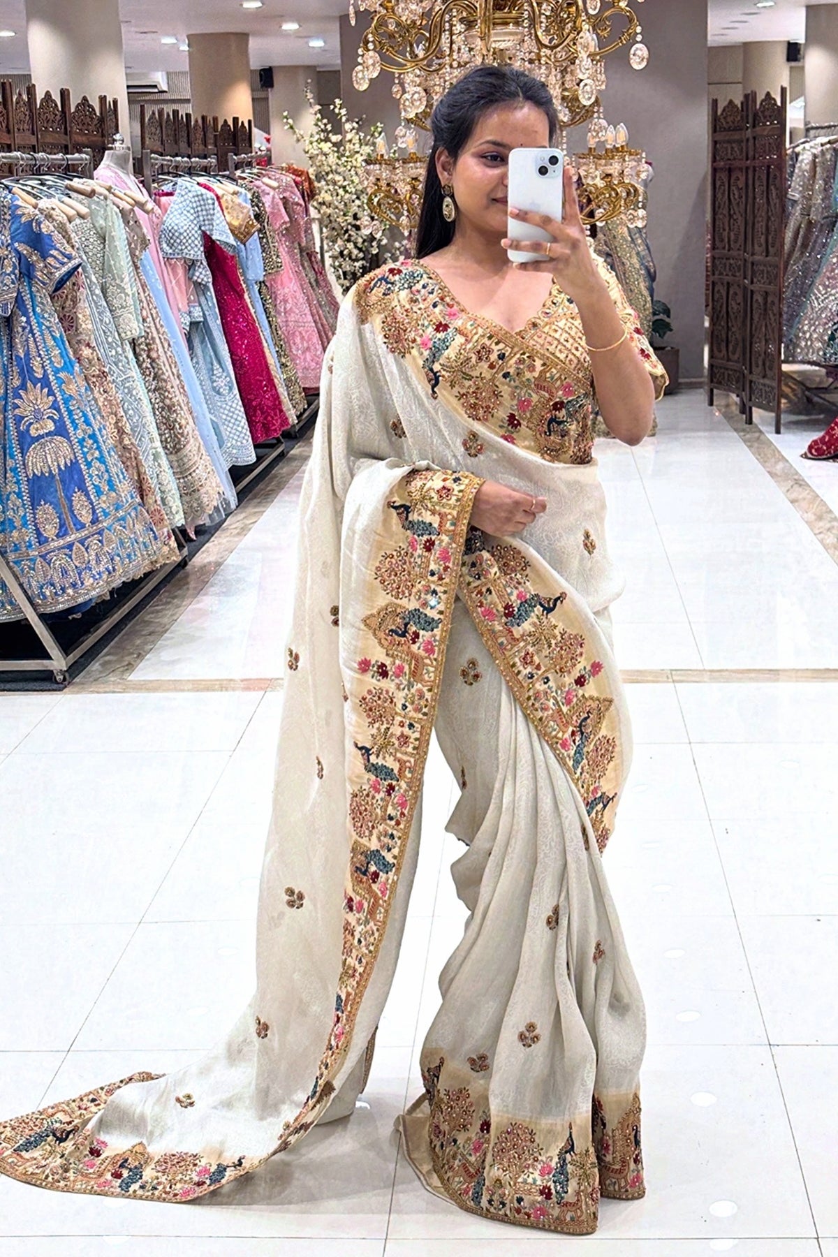 Close-up of a designer ivory V-neck blouse featuring intricate peacock motifs and gold zari work, perfect for a high-end wedding trousseau.