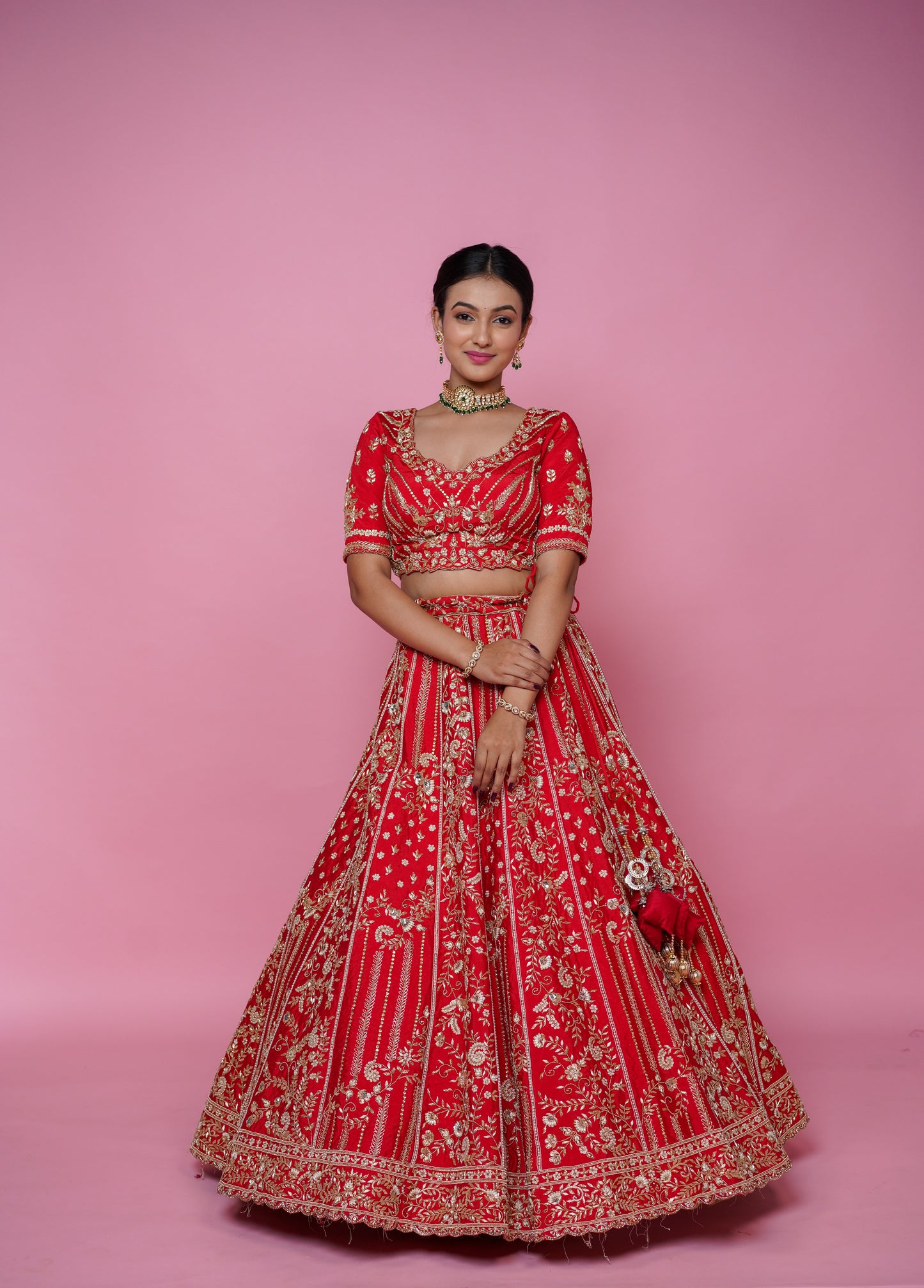 Bride wearing heavy red silk designer lehenga with Cutdana, pearl and zarkan handwork