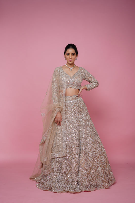 Woman wearing a gorgeous beige gold designer lehenga for engagement ceremony