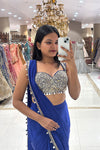 Woman taking a mirror selfie in a luxury boutique wearing a royal blue Indo-Western pre-draped saree with a heavy mirror-work sweetheart bustier at Urban Dulhaniya.