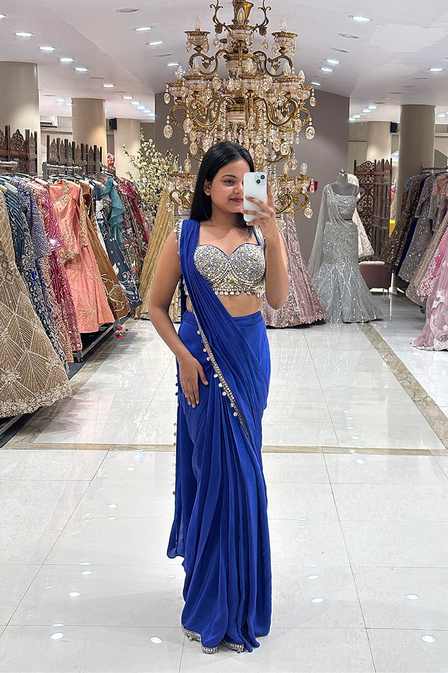 Full-length view of a designer royal blue concept saree with metallic coin borders and an embellished blouse, showcased in a premium bridal store setting.