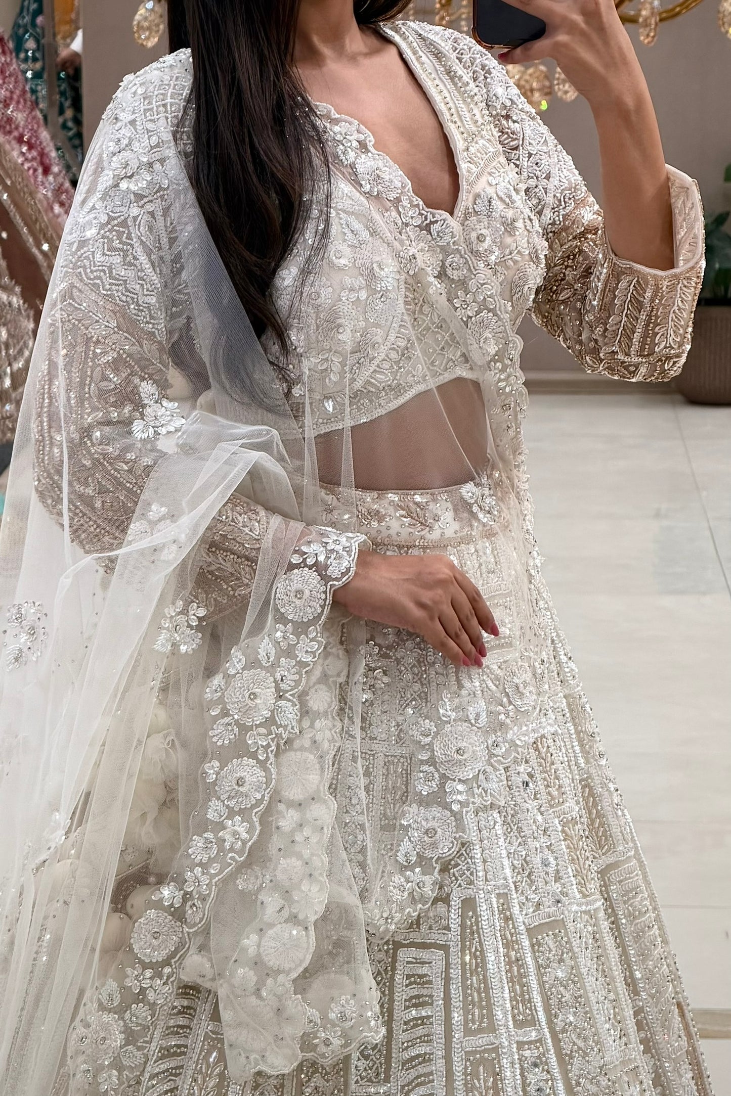 White bridal lehenga blouse with 3D floral V-neckline and sheer midriff panel – Urban Dulhaniya Pune
