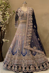 Intricate silver and pink stonework on an ombre blue bridal lehenga skirt paired with a heavy bordered net dupatta.