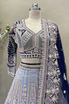 Close-up detail of a designer midnight blue V-neck lehenga blouse with long sleeves, heavy silver embroidery, and crystal drop tassels.