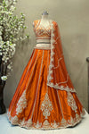 Tangerine orange raw silk lehenga set with vertical beadwork panels and scalloped dupatta for bridal wear.