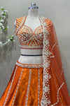 Close-up of intricate silver beads work and sequin embroidery on an orange designer bridal choli.