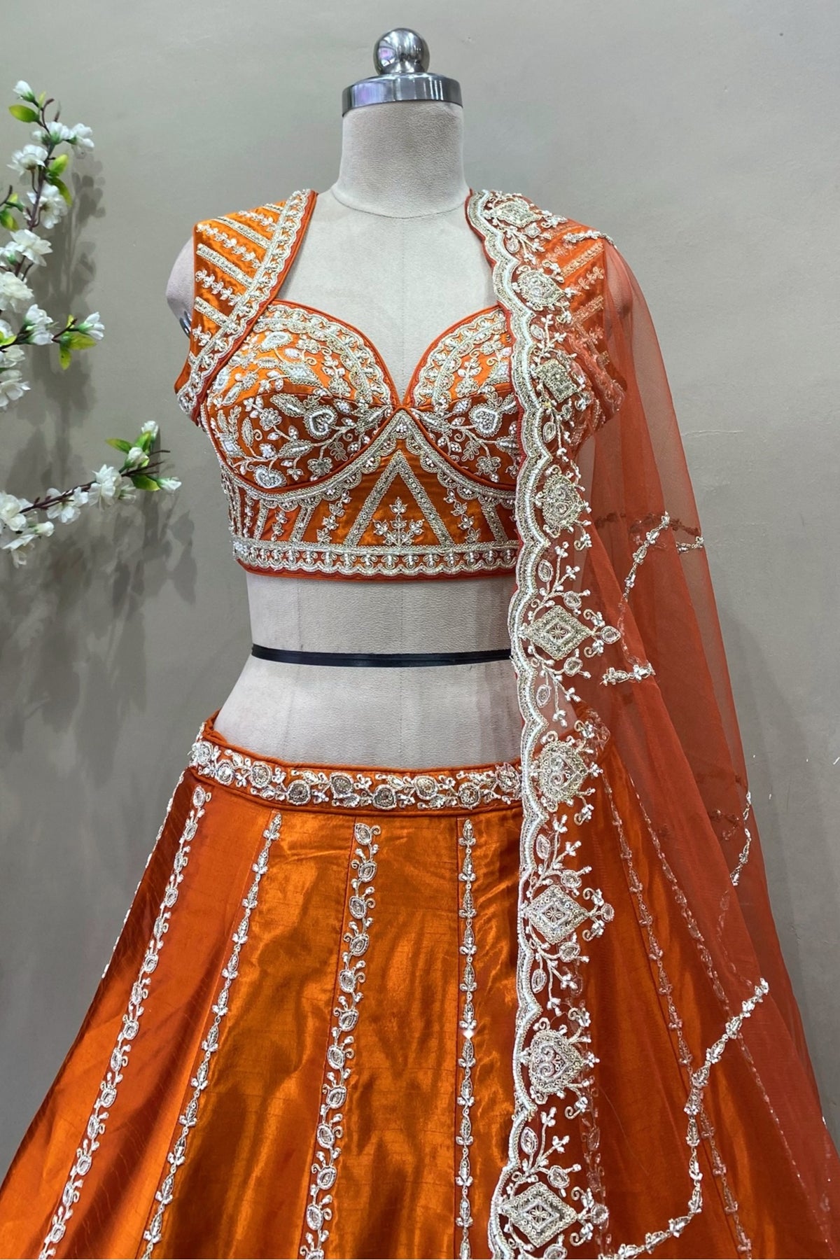 Close-up of intricate silver beads work and sequin embroidery on an orange designer bridal choli.