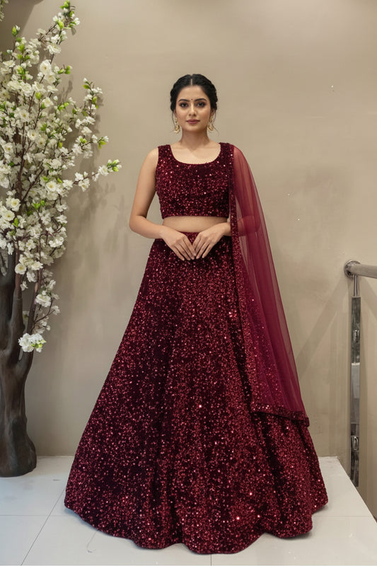 Full-length view of a luxury deep maroon all-over sequin designer lehenga displayed on a mannequin at the Urban Dulhaniya boutique.