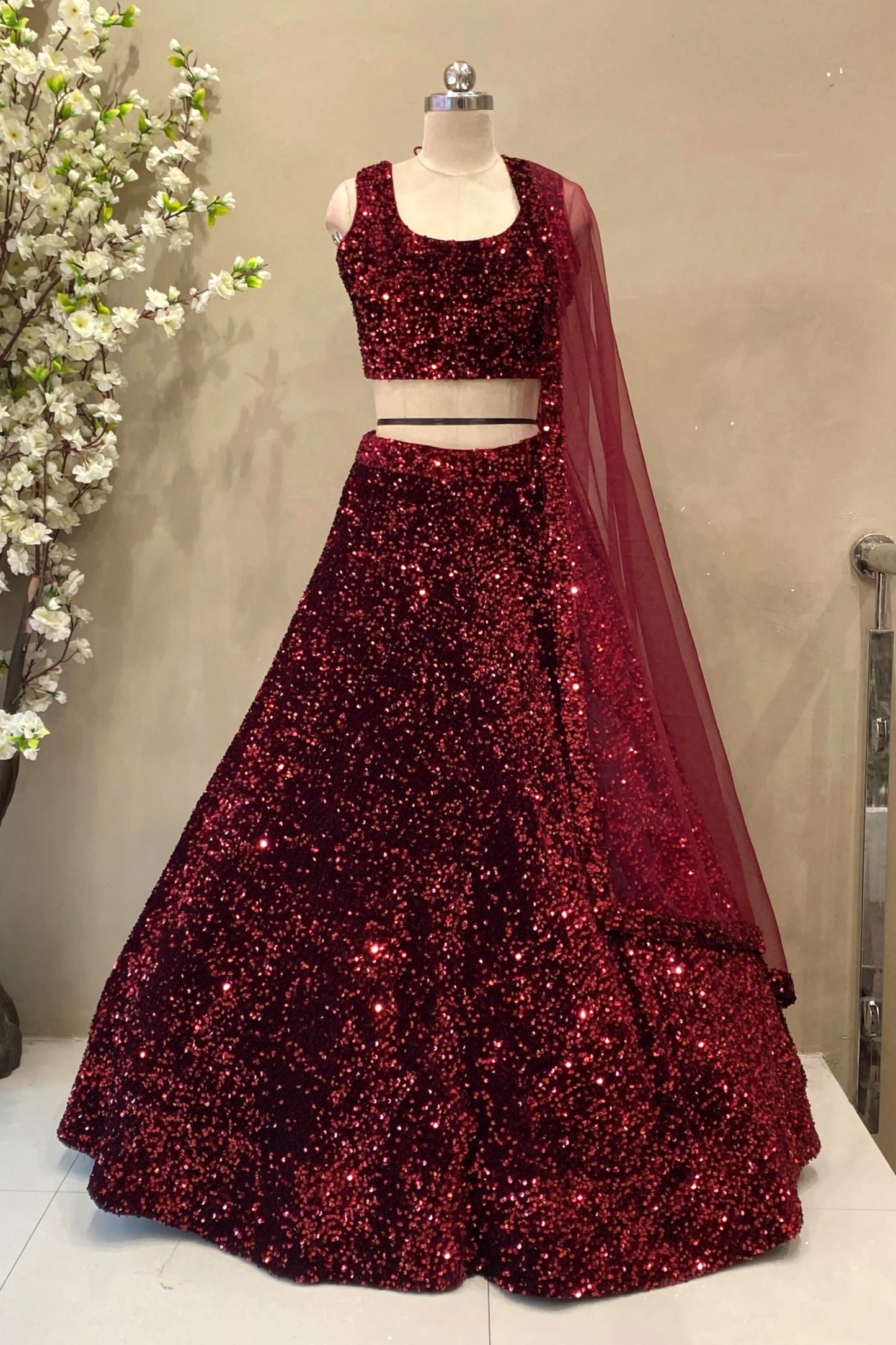 Full-body shot showcasing the voluminous flared skirt and dense sequin fabrication of a premium ruby red sangeet lehenga.