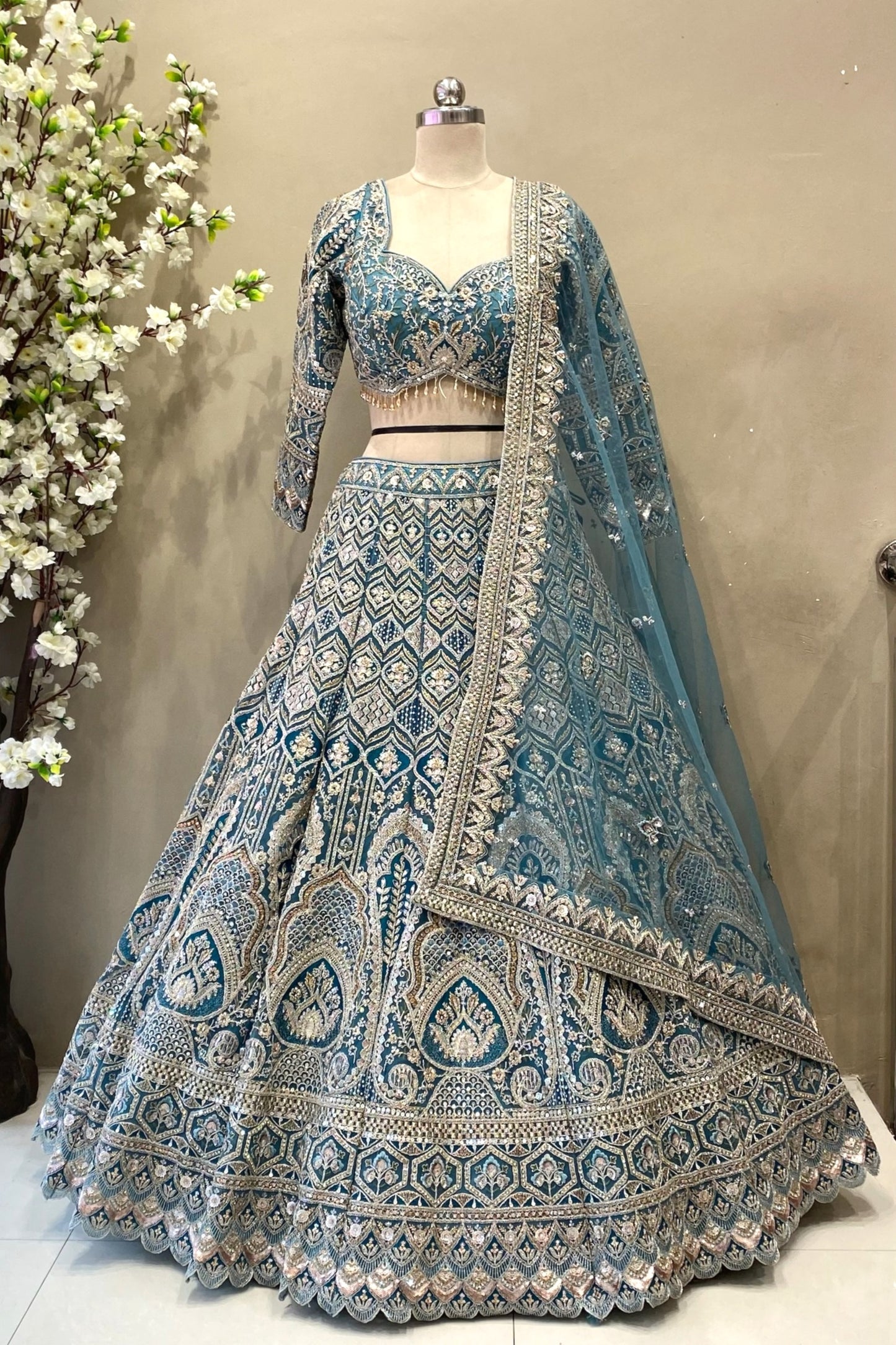 Detail shot highlighting the dense geometric sequin and crystal beadwork on a flared teal blue reception lehenga skirt.