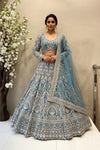 Full-length view of a luxury teal blue heavy embroidered bridal lehenga featuring geometric silver work and a scalloped dupatta displayed on a mannequin at the Urban Dulhaniya boutique.