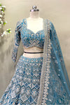 Close-up of a premium designer teal lehenga blouse showcasing a sweetheart neckline, three-quarter sleeves, heavy zardosi embroidery, and beaded fringe tassels.