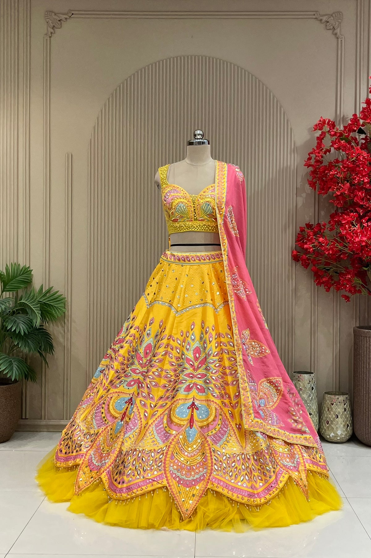 Yellow lehenga set showing embellished skirt pattern and pink dupatta drape