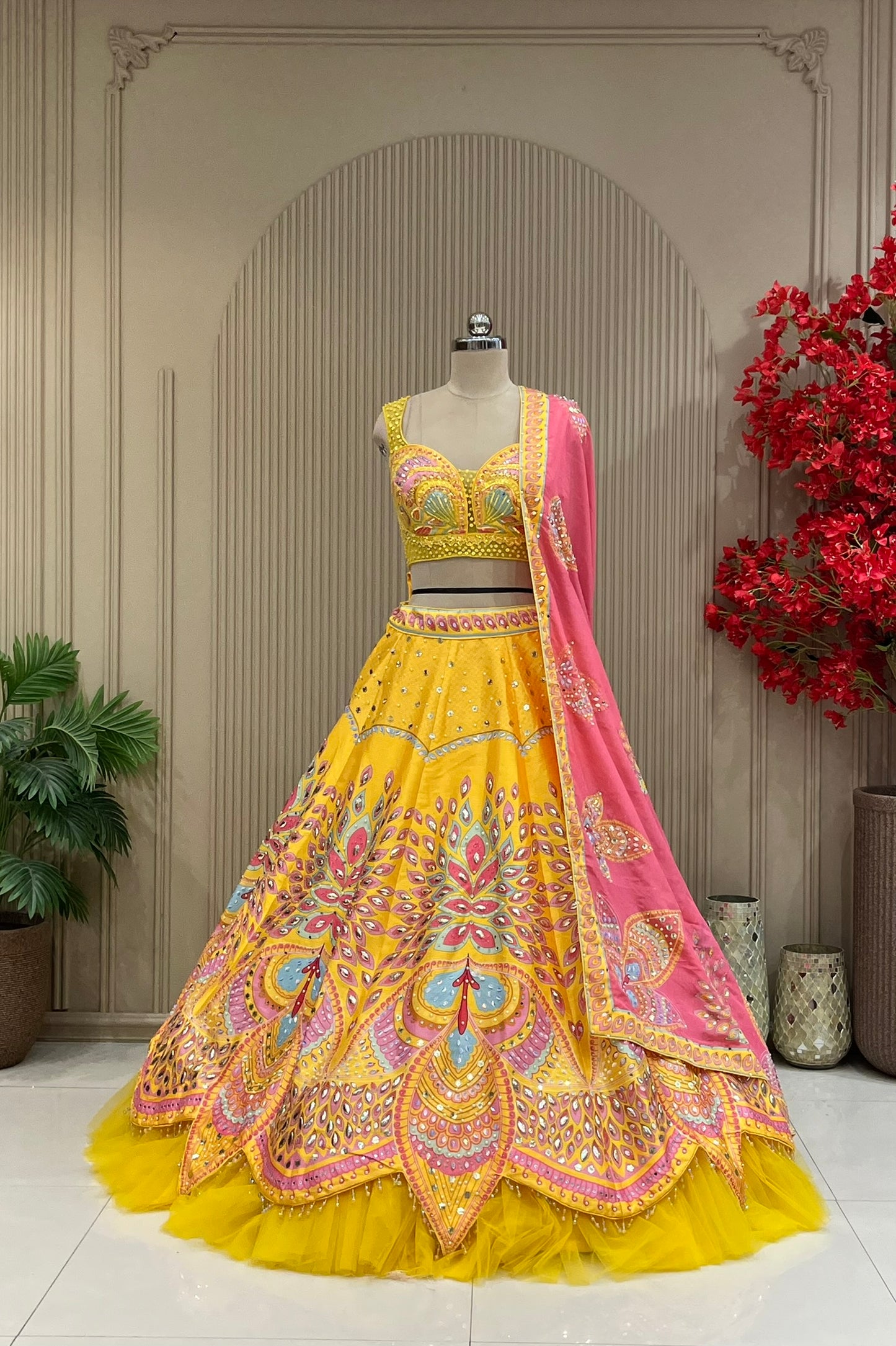 Yellow lehenga set showing embellished skirt pattern and pink dupatta drape