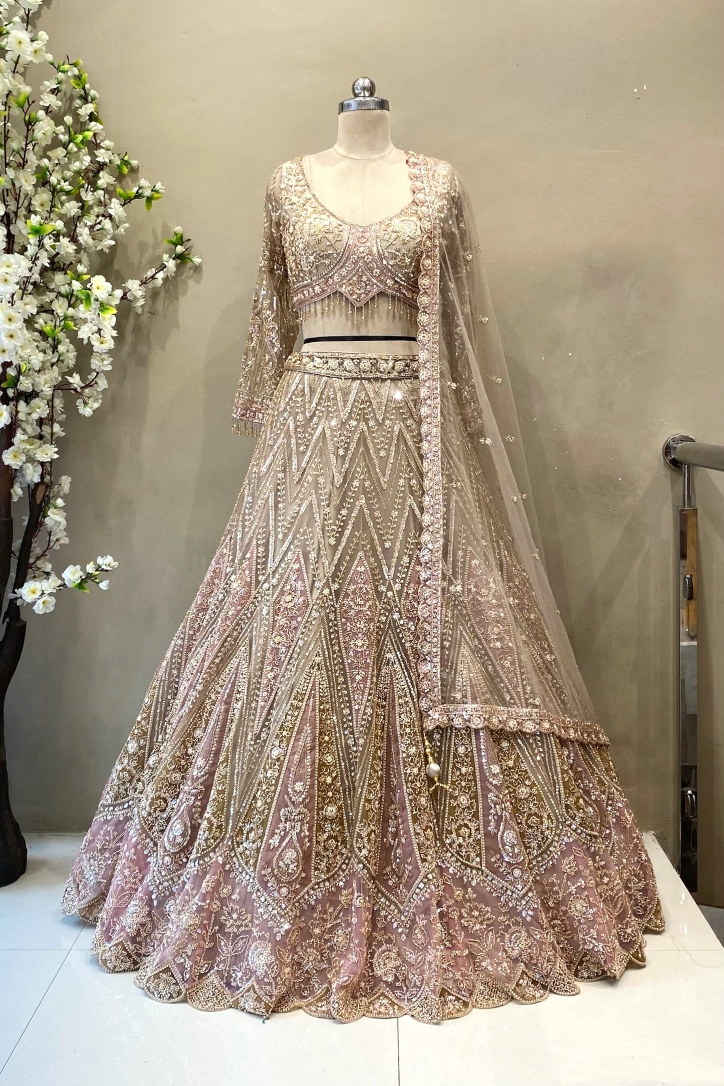 Detailed shot of a flared champagne and pink lehenga skirt featuring dense geometric beadwork and a heavy scalloped border.