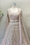 Close-up of a designer long-sleeve bridal blouse with sheer sleeves, crystal fringe tassels, and intricate pink floral beadwork.