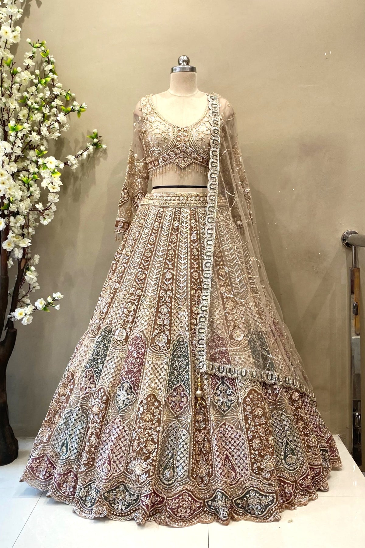 etailed shot of a flared antique gold lehenga featuring dense multi-color heavy beads work and a wide scalloped border.