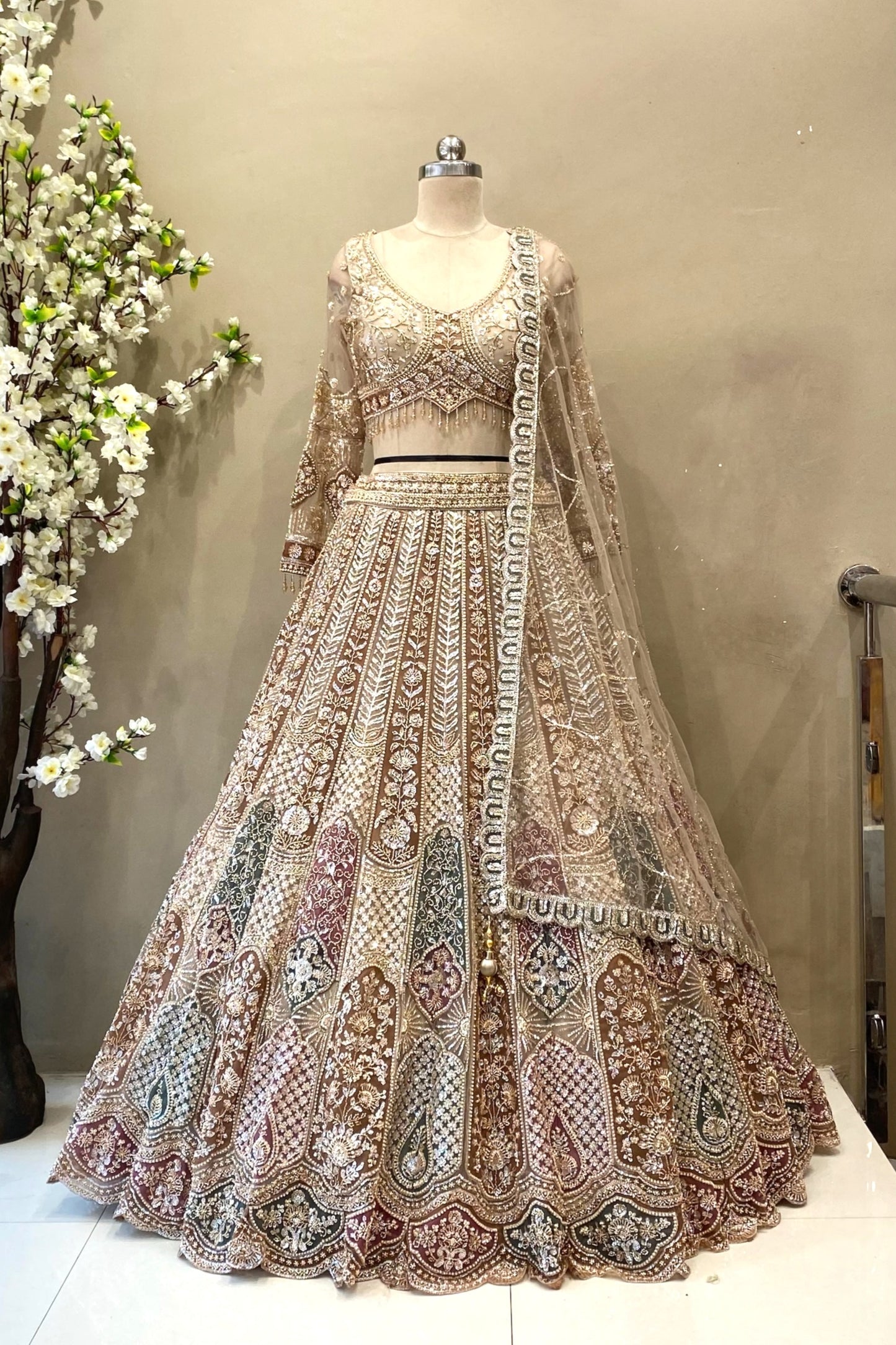 etailed shot of a flared antique gold lehenga featuring dense multi-color heavy beads work and a wide scalloped border.