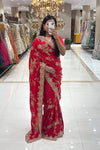Full-length view of a woman taking a mirror selfie wearing a luxury classic red pure handwork designer saree with heavy gold floral borders, showcased at the Urban Dulhaniya boutique in Pune