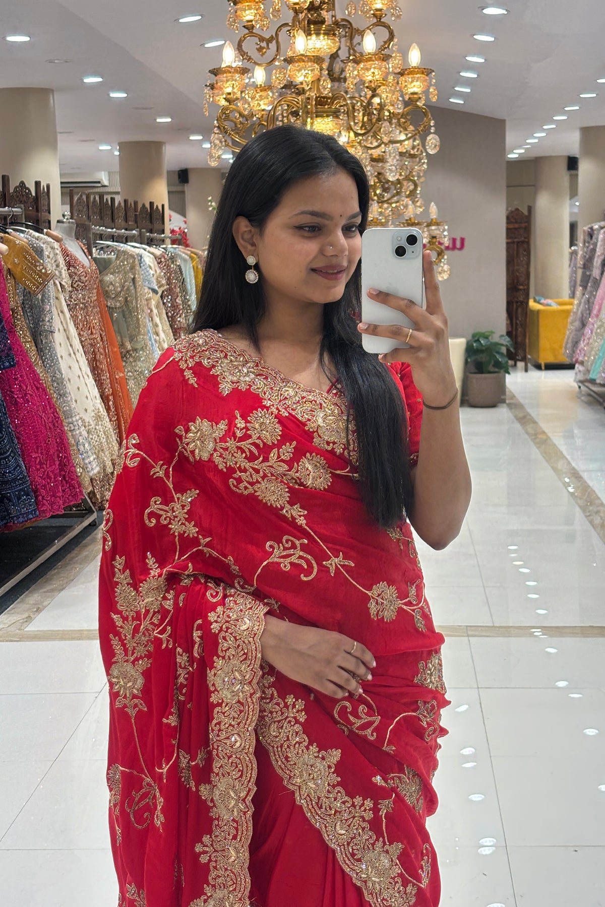 Close-up of a premium pure handwork red bridal saree highlighting the intricate gold zardosi and floral embroidery along the drape and scalloped edges.