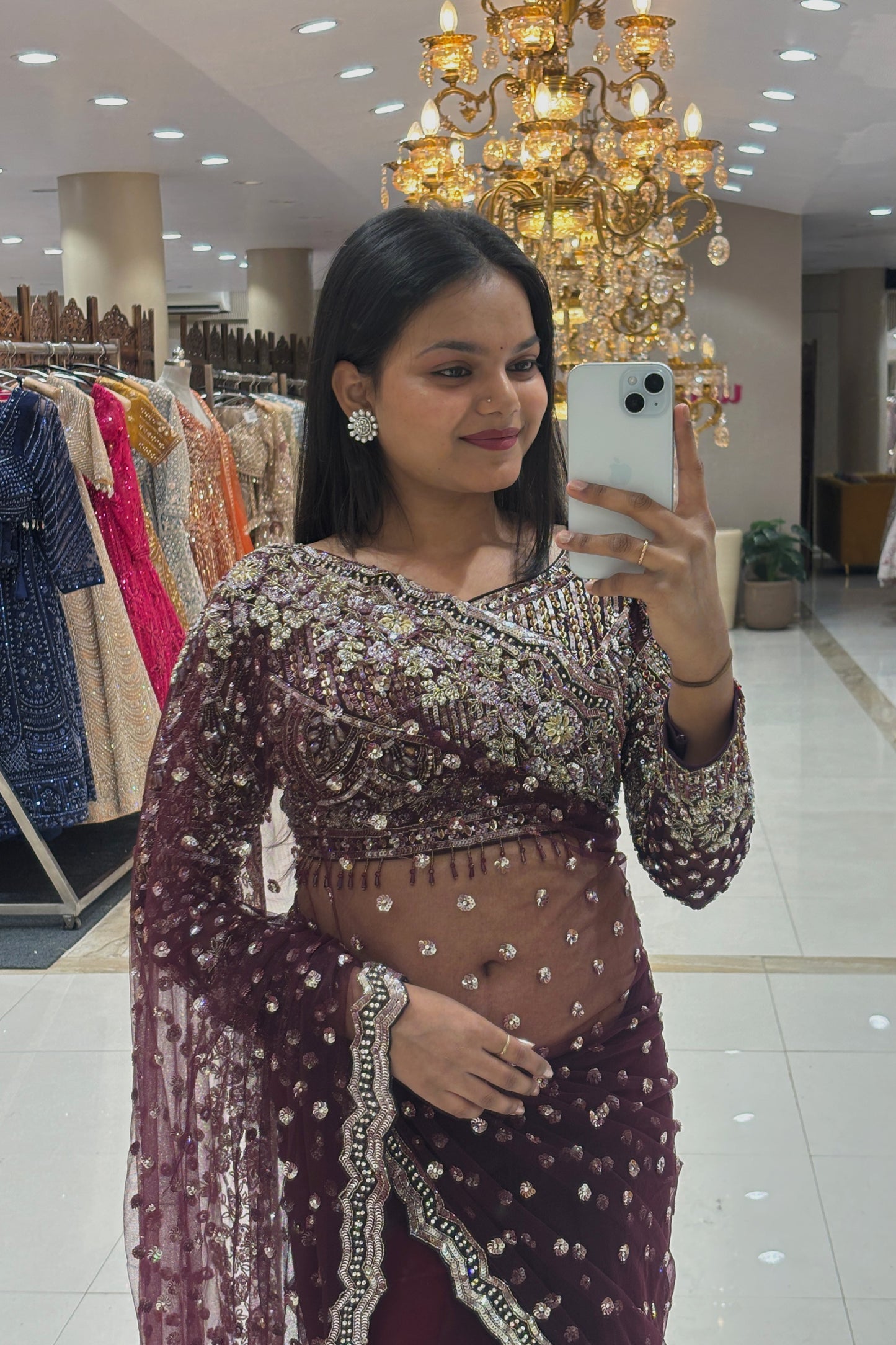 Mid-length view of a premium deep wine party wear saree showcasing a scalloped embroidered border and scattered sequin motifs on sheer net fabric.