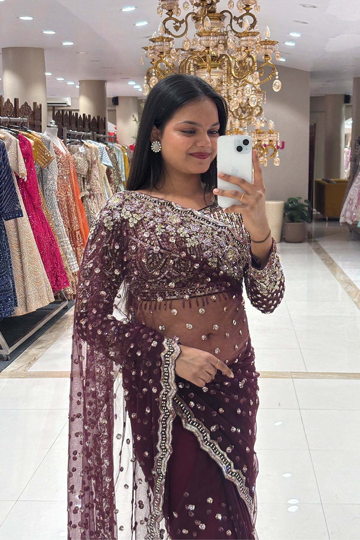 Close-up of a designer long-sleeve blouse featuring heavy pure handwork, crystal embellishments, and beaded tassels on a burgundy net reception saree.