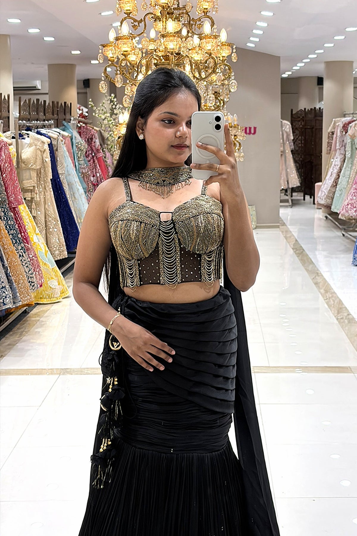 Close-up of a designer sheer black corset blouse featuring pure handwork gold bead and chain embellishments, paired with a ruched black mermaid skirt.