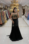 Woman taking a mirror selfie in a luxury Indo-Western black fishcut lehenga with an attached cape and a heavy gold handwork corset blouse at Urban Dulhaniya boutique.