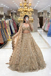 Full-length mirror selfie of a bride wearing a luxury champagne gold heavy handwork bridal lehenga with a scalloped dupatta at the Urban Dulhaniya boutique.