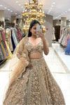 Close-up of a designer golden V-neck lehenga blouse featuring pure handwork crystal and zardosi embroidery, paired with a sheer net scalloped dupatta.