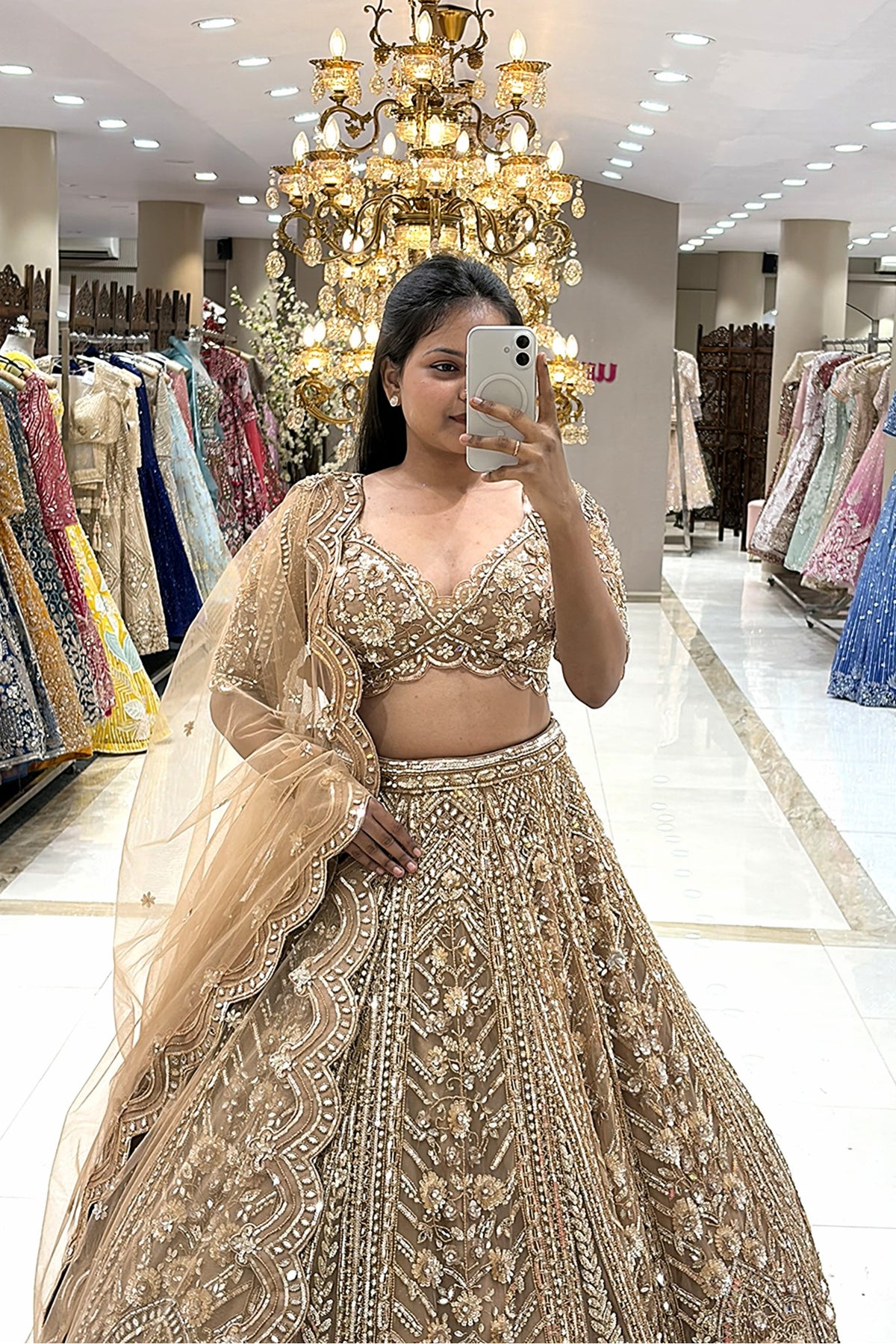 Close-up of a designer golden V-neck lehenga blouse featuring pure handwork crystal and zardosi embroidery, paired with a sheer net scalloped dupatta.