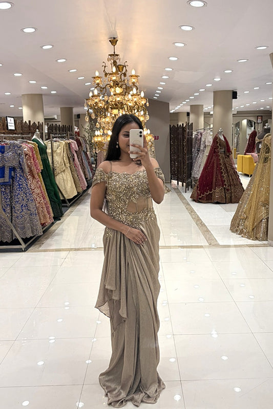 Full-length view of a woman taking a mirror selfie wearing a luxury champagne gold draped Indo-Western gown with an embellished sheer bodice at the Urban Dulhaniya boutique.