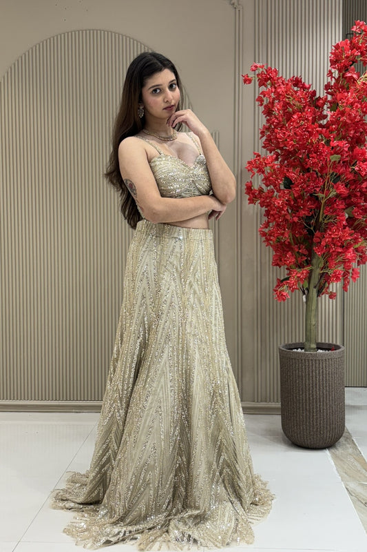Woman wearing a champagne gold shimmer lehenga with a linear sequin pattern and a strappy designer blouse at Urban Dulhaniya boutique on MG Road, Pune.