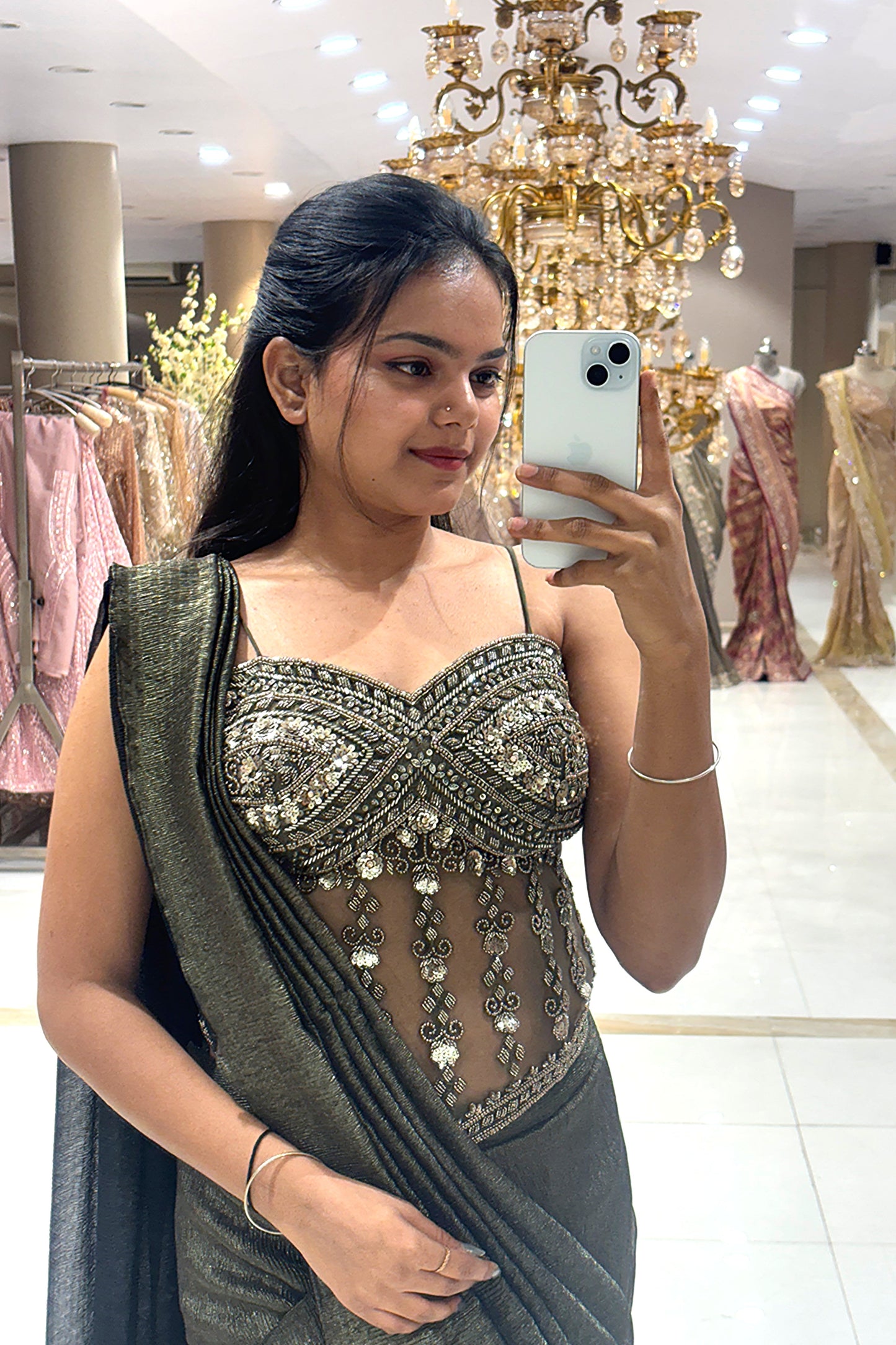 Close-up of a designer sheer corset blouse featuring pure handwork crystal and bead embroidery, paired with a pleated metallic shimmer drape for cocktail parties.
