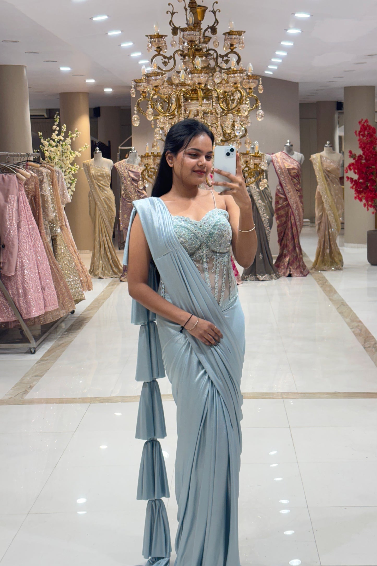 Close-up of a designer sheer corset blouse featuring silver crystal embroidery, paired with a pleated powder blue shimmer drape and ruffled pallu for cocktail parties.