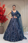 Midnight navy designer lehenga on a model featuring heavy hand-embroidery with cutdana, sequins, and metallic beads, paired with a modern sleeveless V-neck blouse.