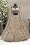 Full-length view of a luxury silver crystal embellished designer bridal lehenga with sheer long sleeves displayed on a mannequin at the Urban Dulhaniya boutique.