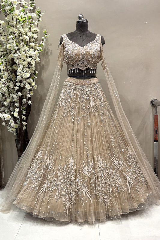 Full-length view of a luxury silver crystal embellished designer bridal lehenga with sheer long sleeves displayed on a mannequin at the Urban Dulhaniya boutique.