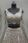 Close-up of a designer silver V-neck lehenga blouse featuring heavy crystal embroidery, cold-shoulder sleeves, and beaded fringe tassels.