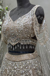Angled close-up detailing the heavy pure handwork and crystal drop hem on a premium reception lehenga blouse
