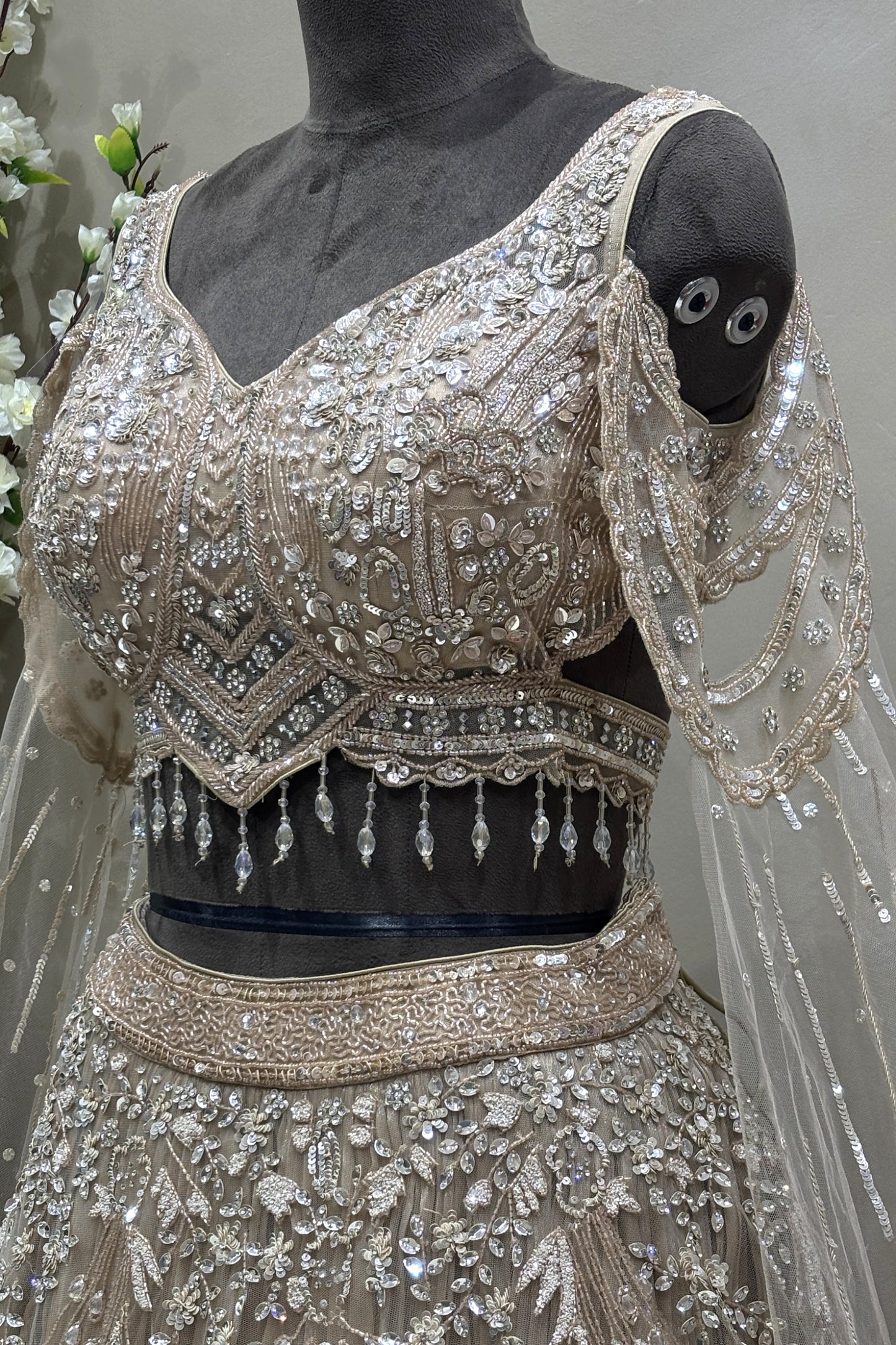 Angled close-up detailing the heavy pure handwork and crystal drop hem on a premium reception lehenga blouse