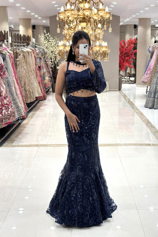 Full-length view of a woman taking a mirror selfie wearing a luxury midnight blue fishcut Indo-Western lehenga with an asymmetrical one-shoulder blouse at the Urban Dulhaniya boutique.