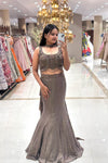 Full-length view of a woman wearing a luxury metallic bronze fishcut Indo-Western lehenga with a heavy handwork sleeveless blouse and choker detail at the Urban Dulhaniya boutique.