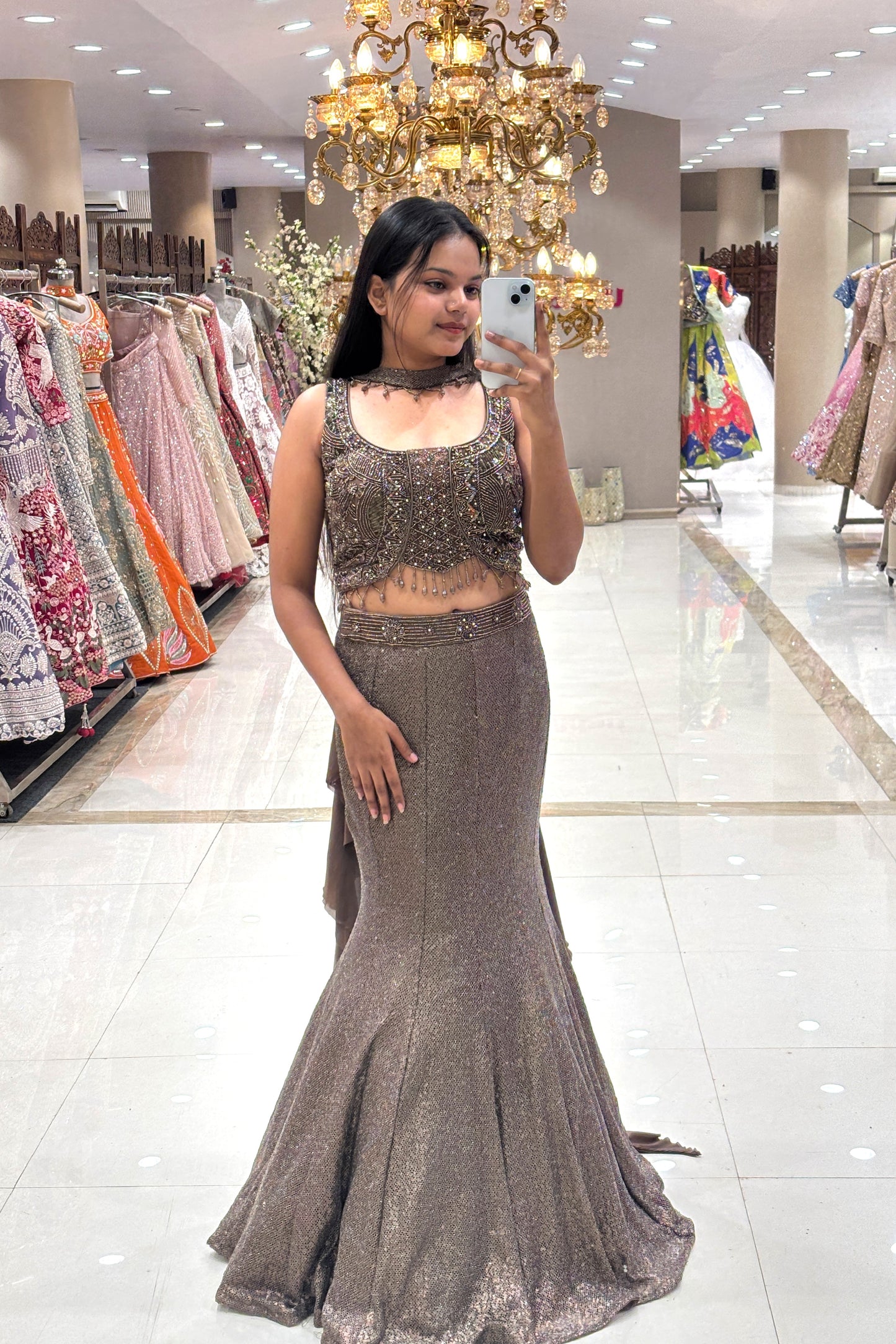 Full-length view of a woman wearing a luxury metallic bronze fishcut Indo-Western lehenga with a heavy handwork sleeveless blouse and choker detail at the Urban Dulhaniya boutique.